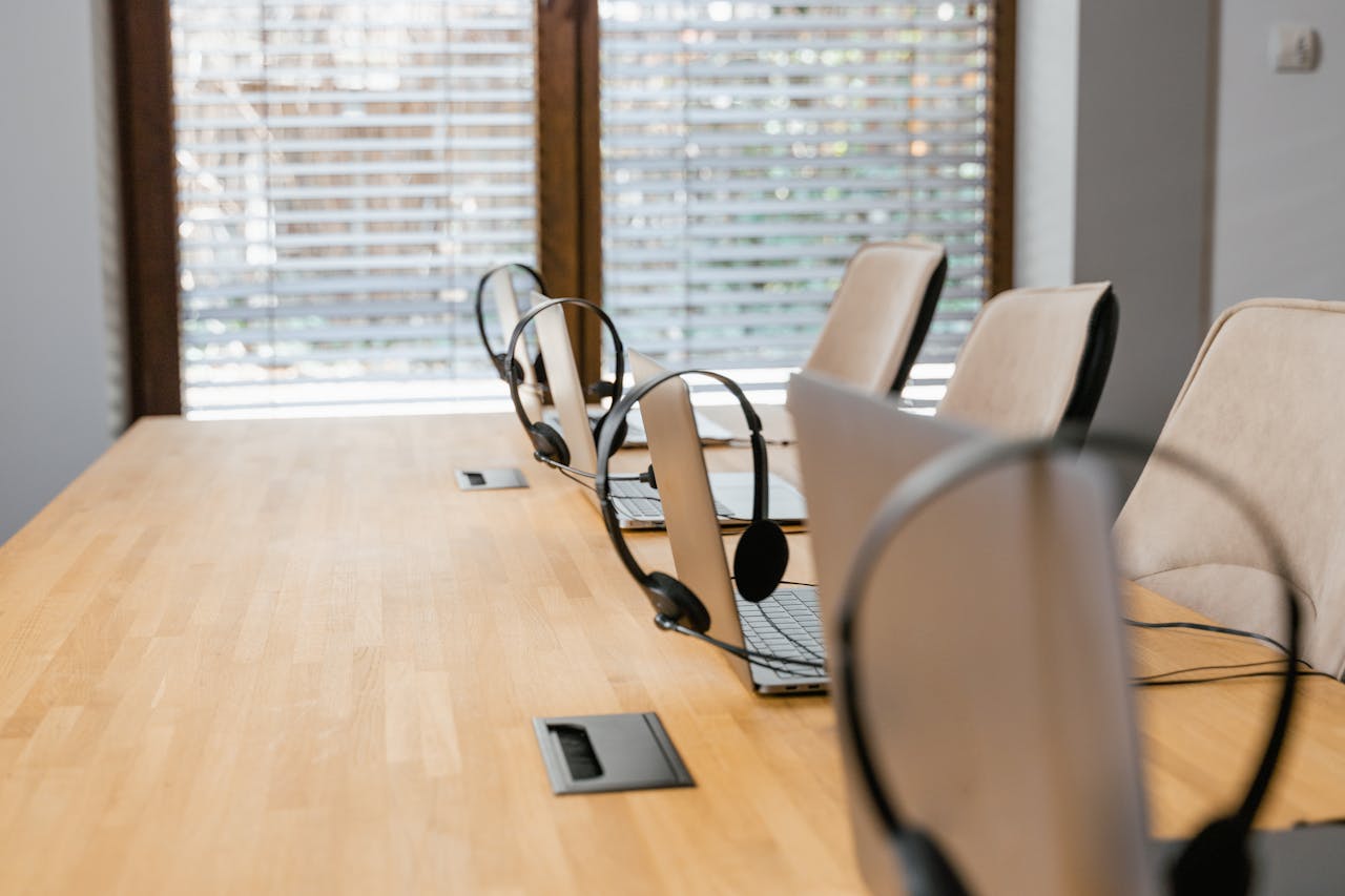 Empty office workspace featuring laptops with headsets, ready for a productive day.